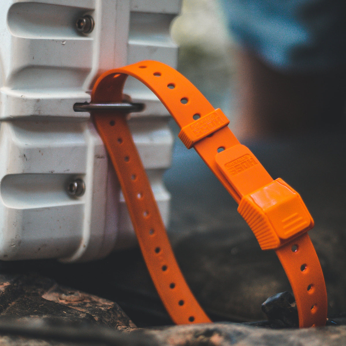 Orange strap attached to a white container on a natural background