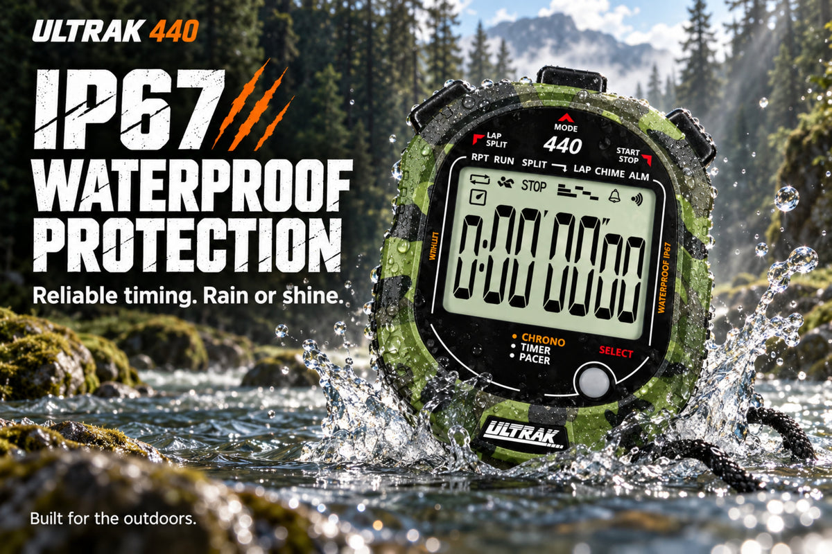 Ultrak 440 waterproof stopwatch shown in a forest stream with water splashing around it, with large text on the left reading 'IP67 WATERPROOF PROTECTION' and 'Reliable timing. Rain or shine.