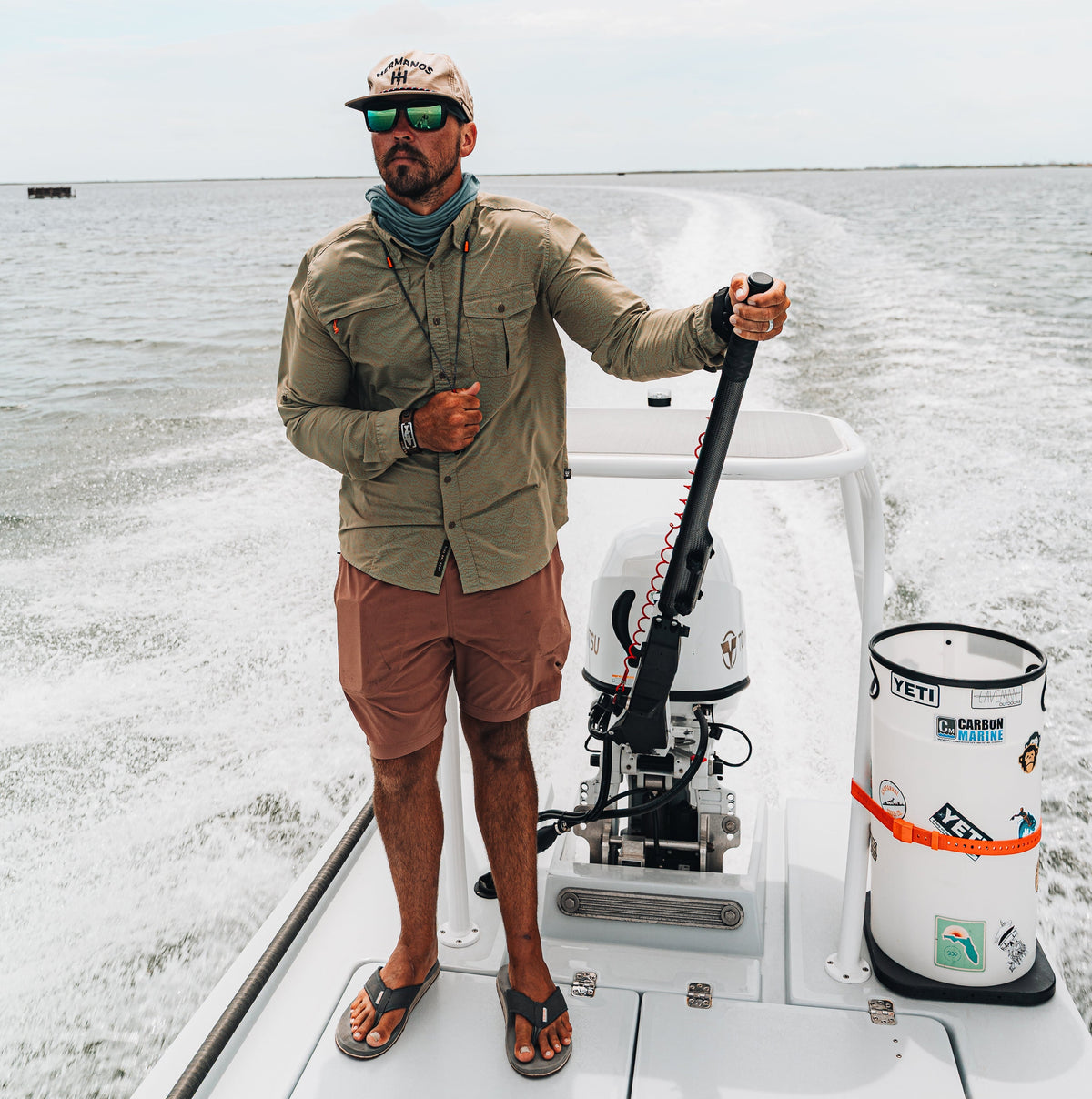 Man on a boat holding a fishing rod with a calm sea and sky in the background