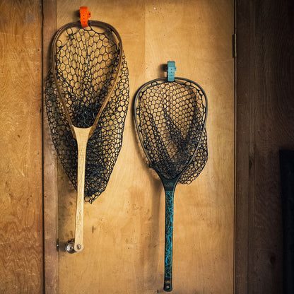Two fishing nets hanging on a wooden wall.
