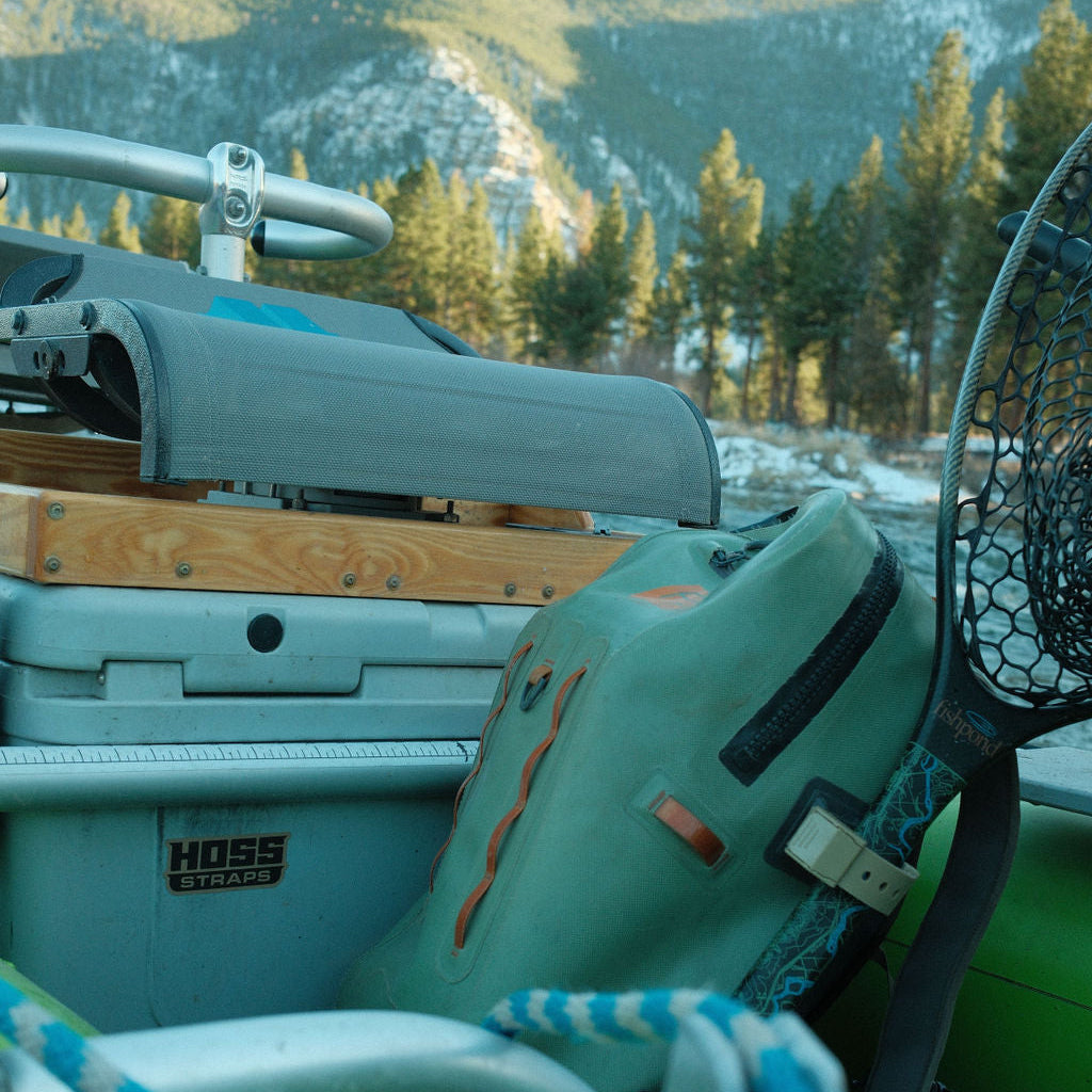 Close-up of a kayak with a fishing net on a vehicle roof, set against a mountainous landscape.